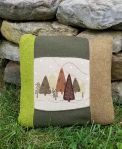 A pillow with trees on it sitting in the grass.