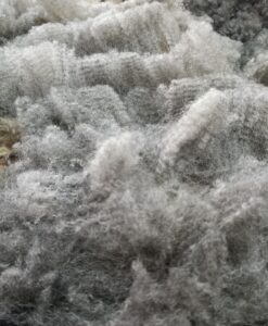 A pile of white and gray wool in the dirt.