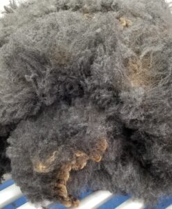 A pile of grey wool on top of a blue cloth.