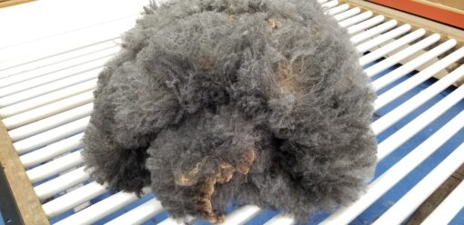 A pile of grey wool on top of a blue cloth.